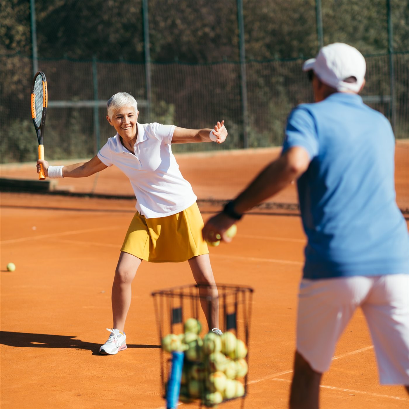 Older adults playing tennis on a sunny court